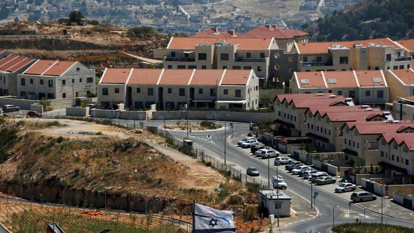 FILE PHOTO: The Israeli national flag flutters as apartments are seen in the background in the Israeli settlement of Efrat in the Israeli-occupied West Bank