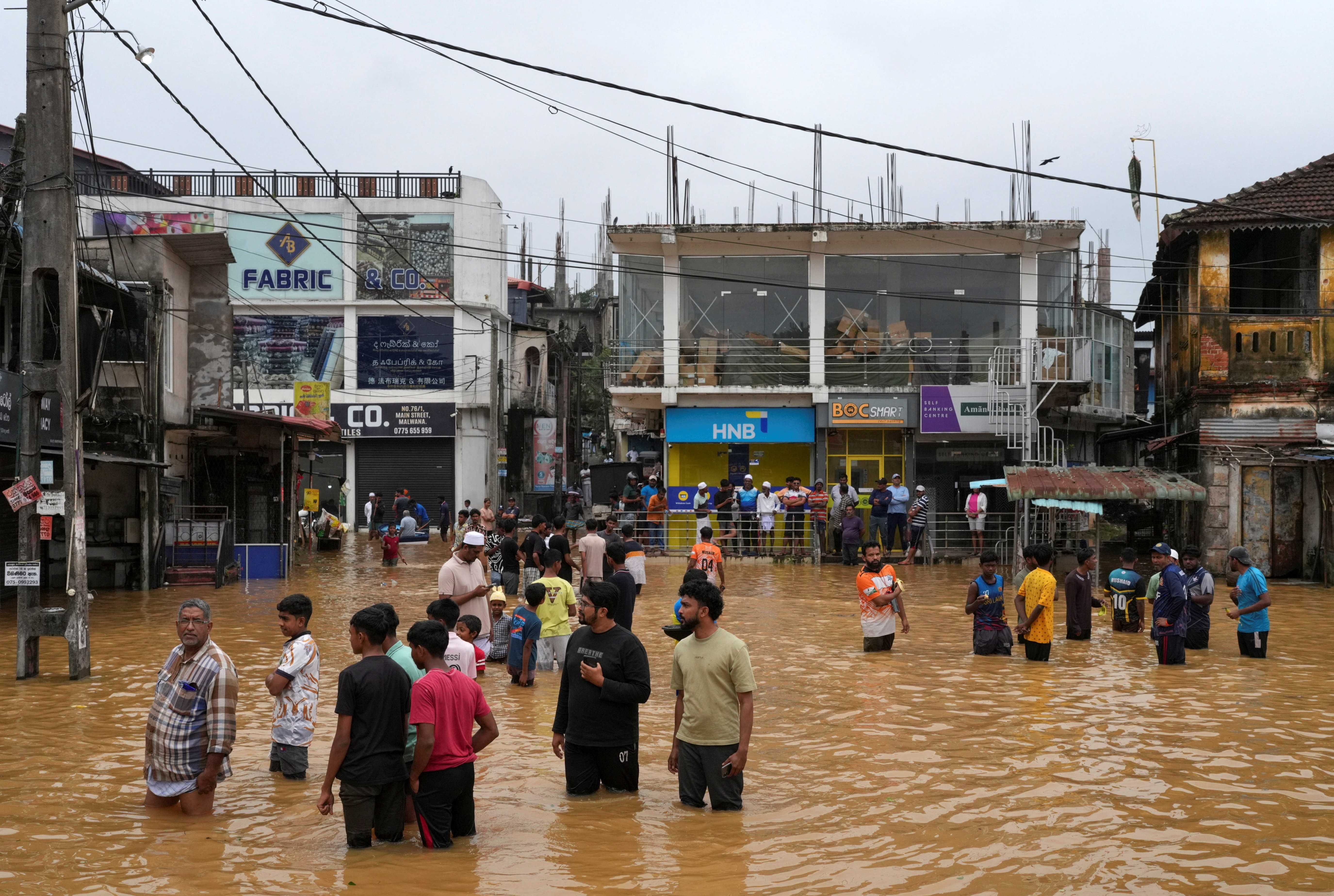 People gather at an area affected by floods, following heavy rainfall in Malwana