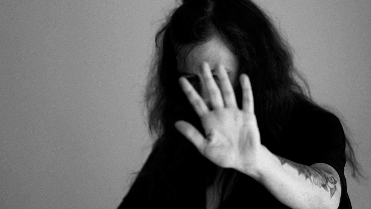 Mulher estende a mão diante do rosto, em sinal de 'pare'
