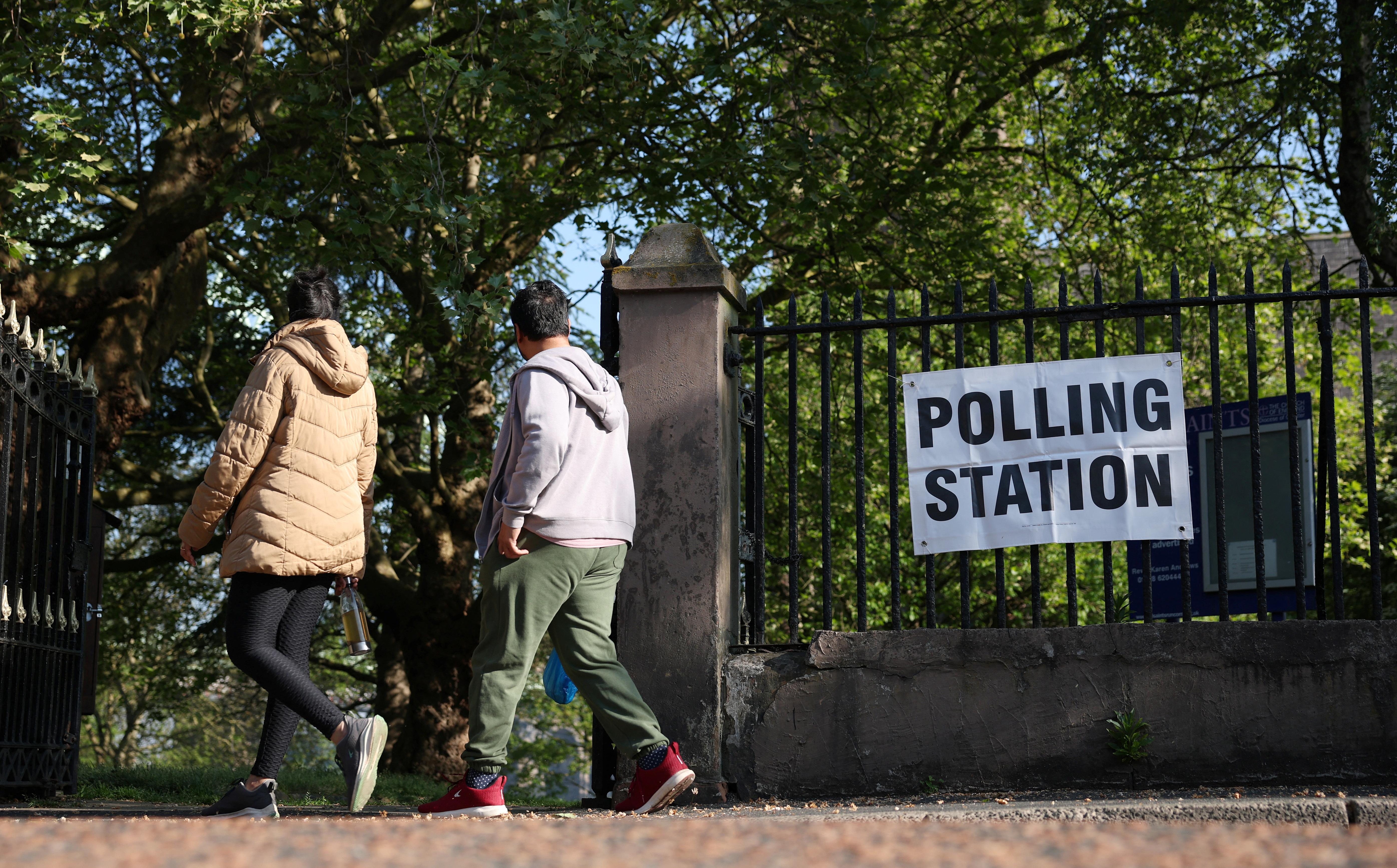 People walk past a polling station sign outside a church as voting gets underway in the Runcorn and Helsby parliamentary by-election in Runcorn, Britain