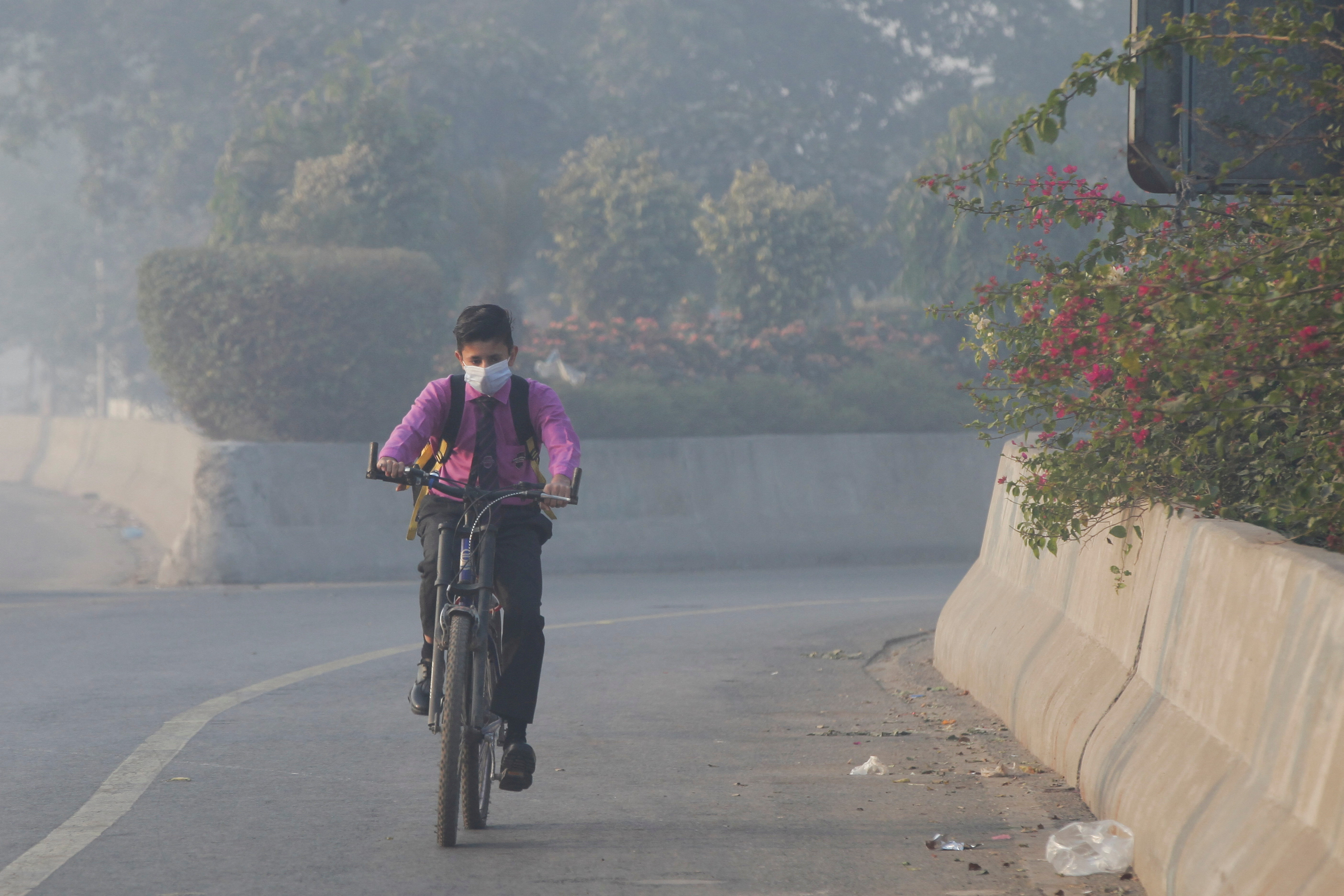 Student rides a bicycle to school amid dense smog in Lahore