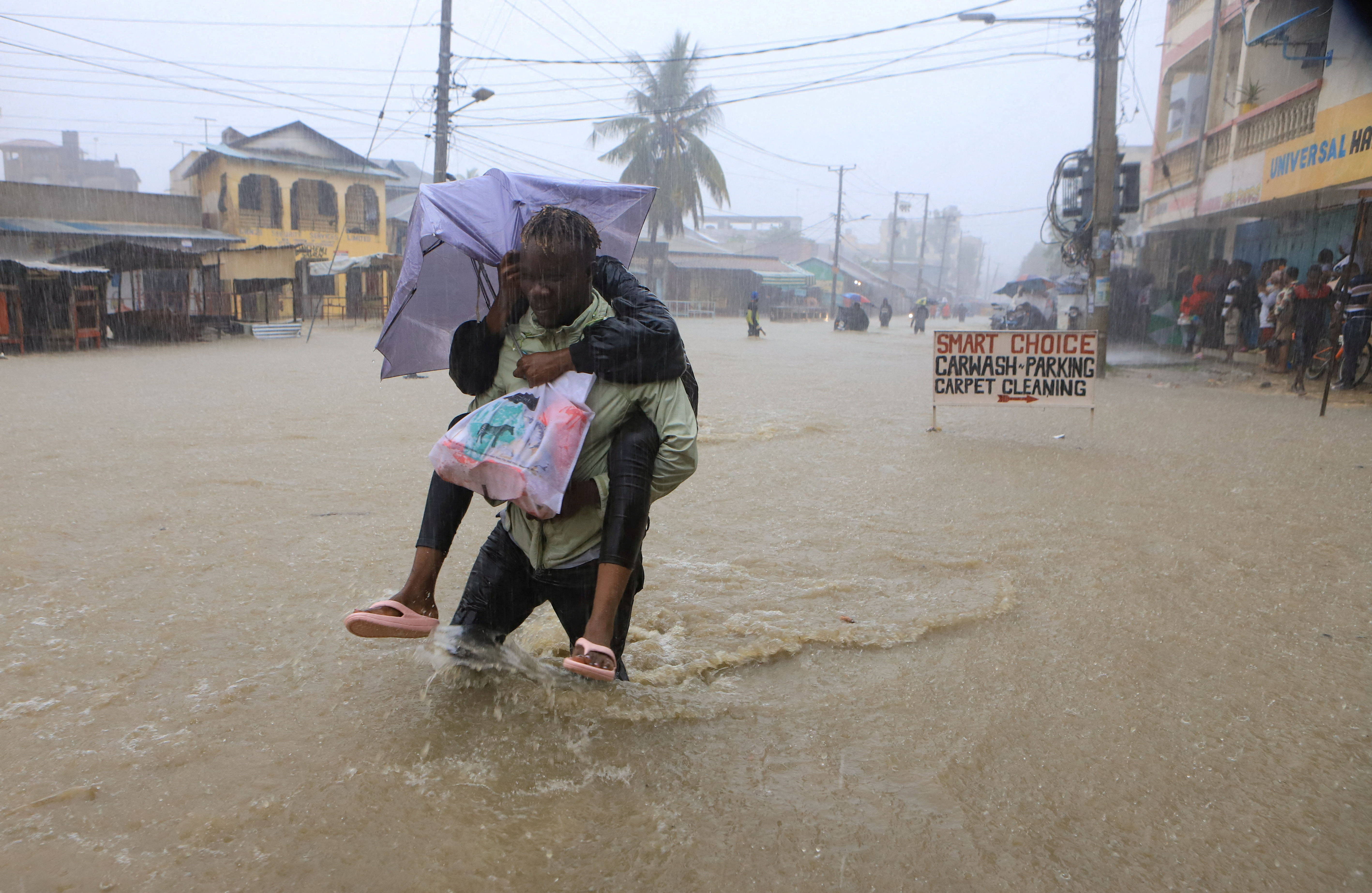 A man wades through flood waters along a street following heavy rains in Kisauni district of Mombasa