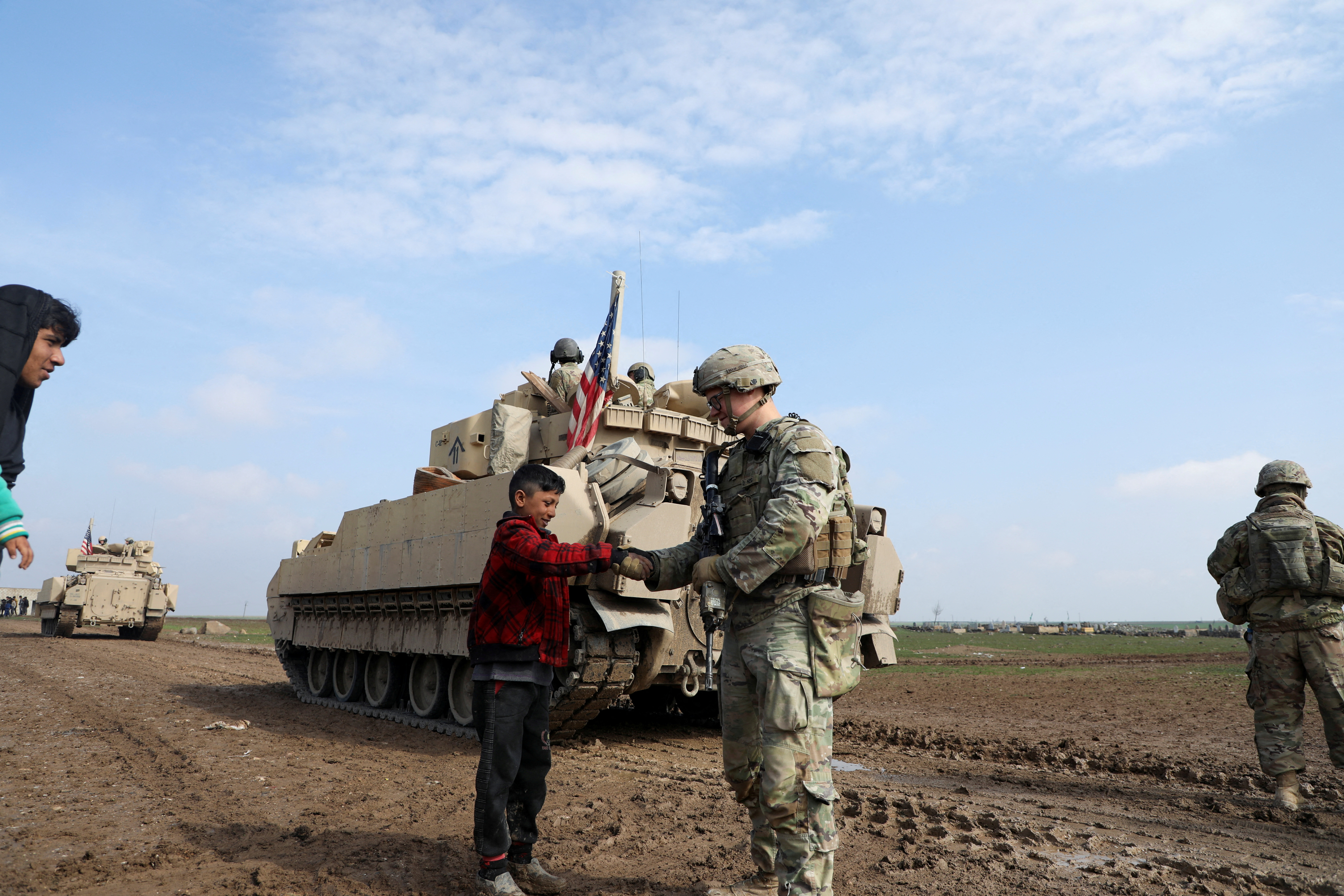 FILE PHOTO: A soldier from the US-led coalition holds the hand of a boy in the countryside of Qamishli