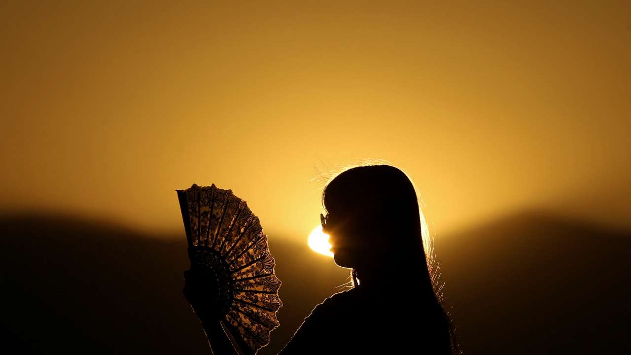 A girl cools off from the heat with a paper fan in Skopje