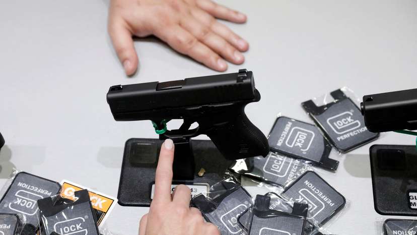 FILE PHOTO: A woman points at a Glock handgun during the annual National Rifle Association (NRA) convention in Dallas, Texas