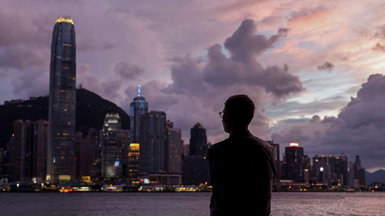 A man stands in front of Victoria Harbour, with the Central financial district in the background, as typhoon Yagi approaches in Hong Kong