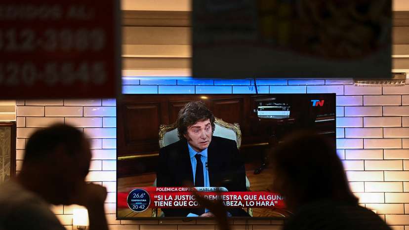People sit in a restaurant as Argentina's President Javier Milei is seen on television, in Buenos Aires