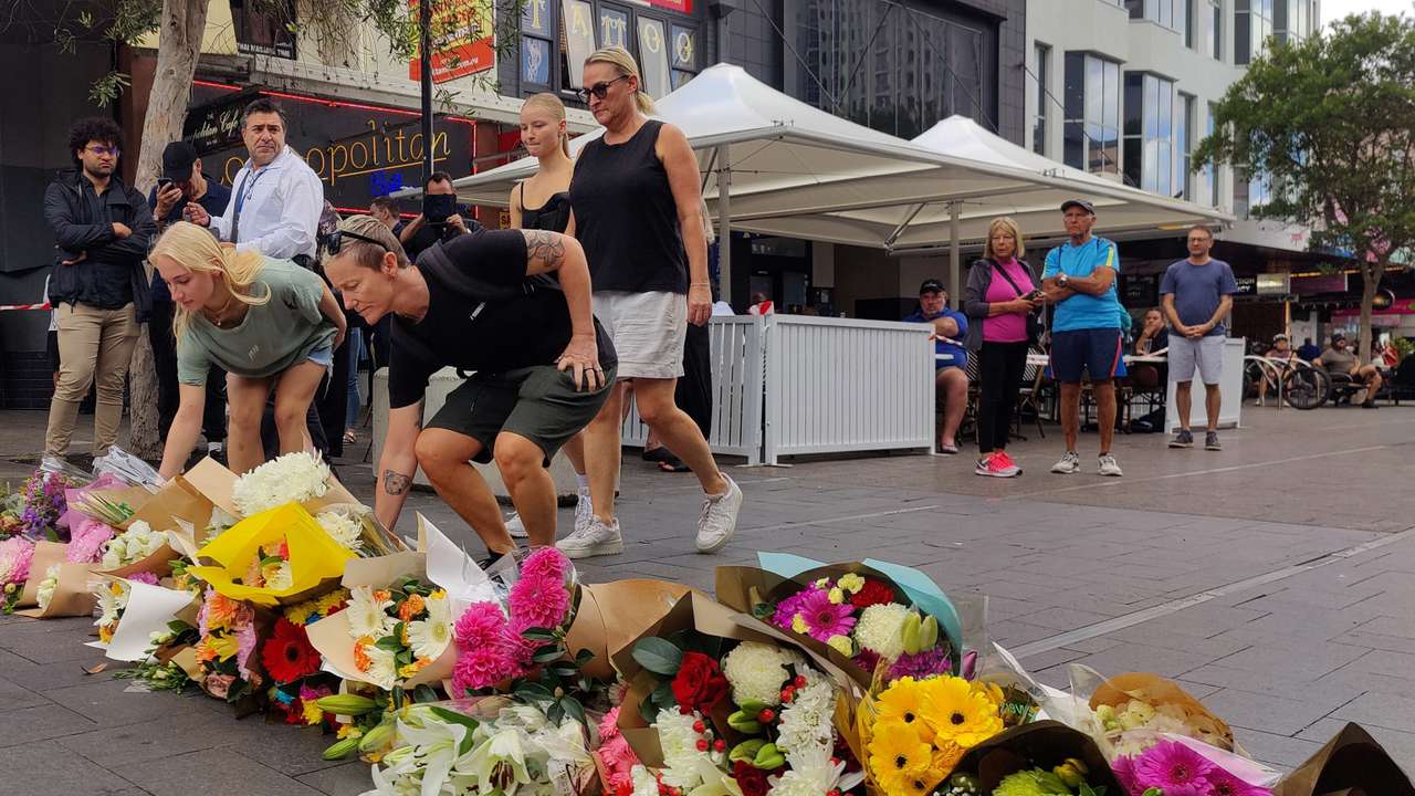 People offer flowers for the victims of Saturday's stabbings at Bondi Junction in Sydney