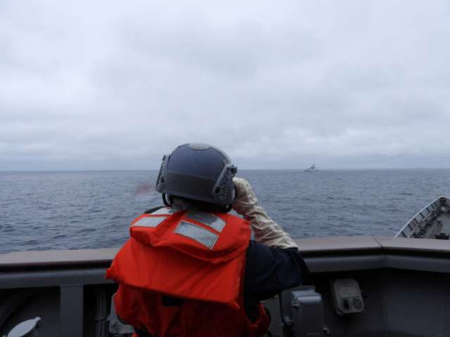 A Taiwanese sailor aboard a Taiwan Navy vessel looks towards a Chinese warship while navigating on waters off Taiwan's western coast