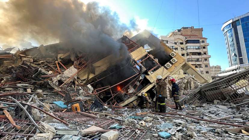 Members of the Lebanese Civil Defence inspect a damaged building after an Israeli strike on Beirut's southern suburbs