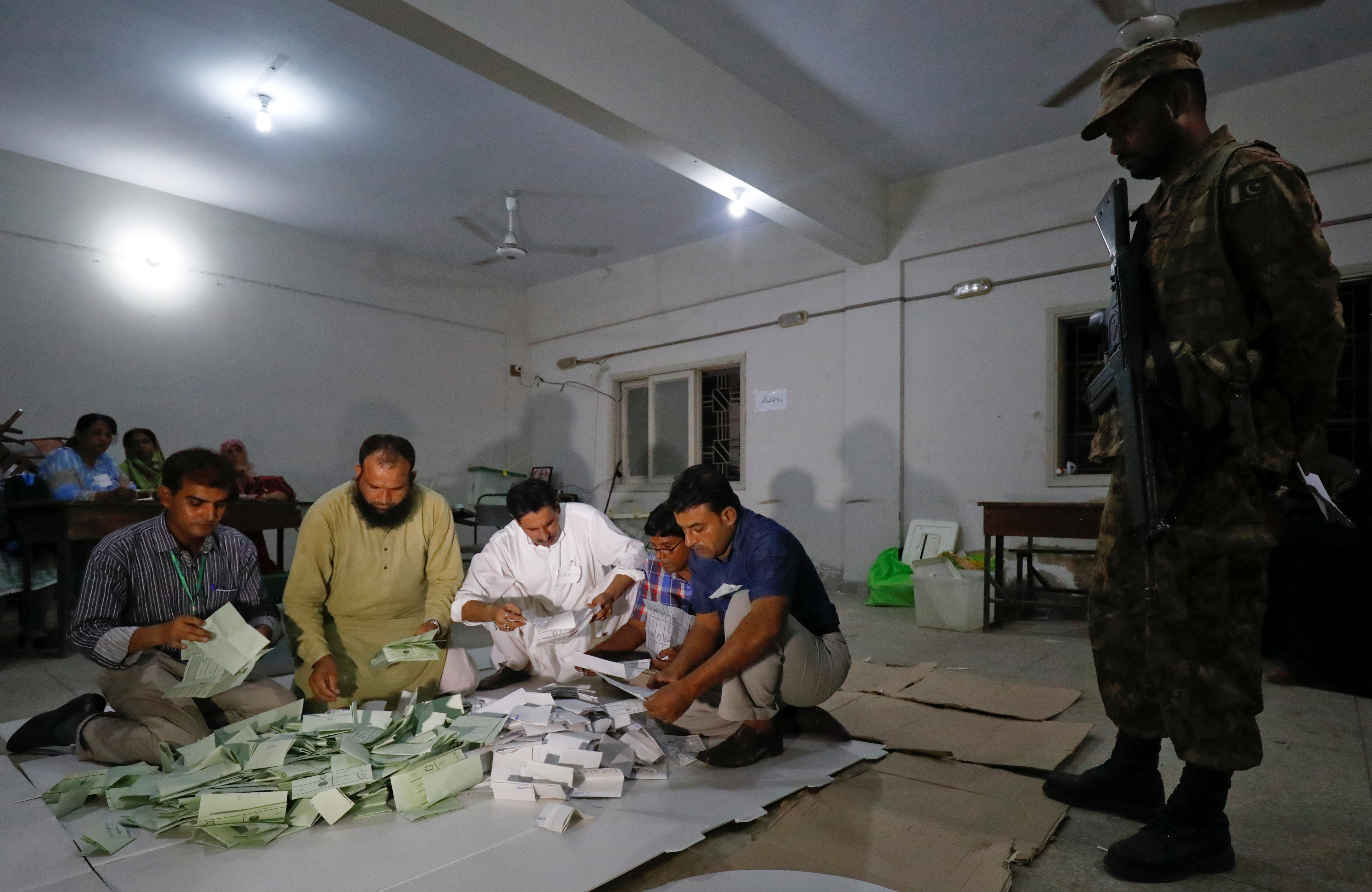 Election officials count votes after polling stations closed during the general election in Karachi