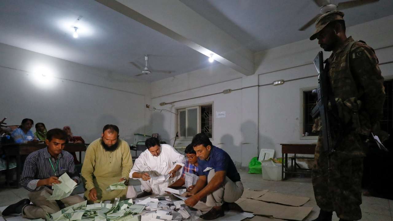 Election officials count votes after polling stations closed during the general election in Karachi