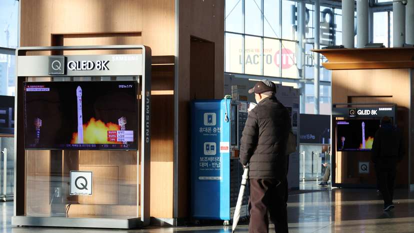 A man watches a TV broadcasting a news report on North Korea launching a military satellite, at a railway station in Seoul