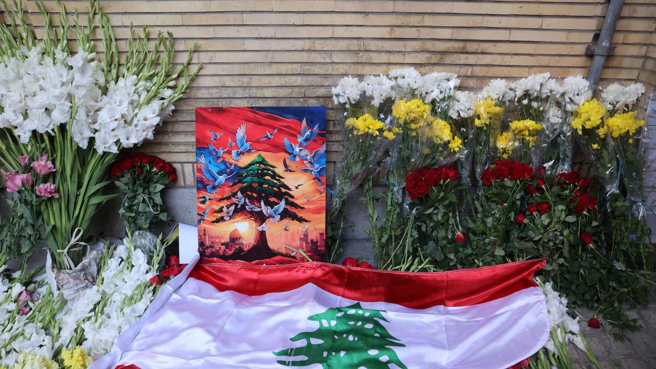 The Lebanese Flag is displayed among the flowers at the gate of Lebanon's Embassy of Iran following the explosion of pagers across Lebanon, in Tehran