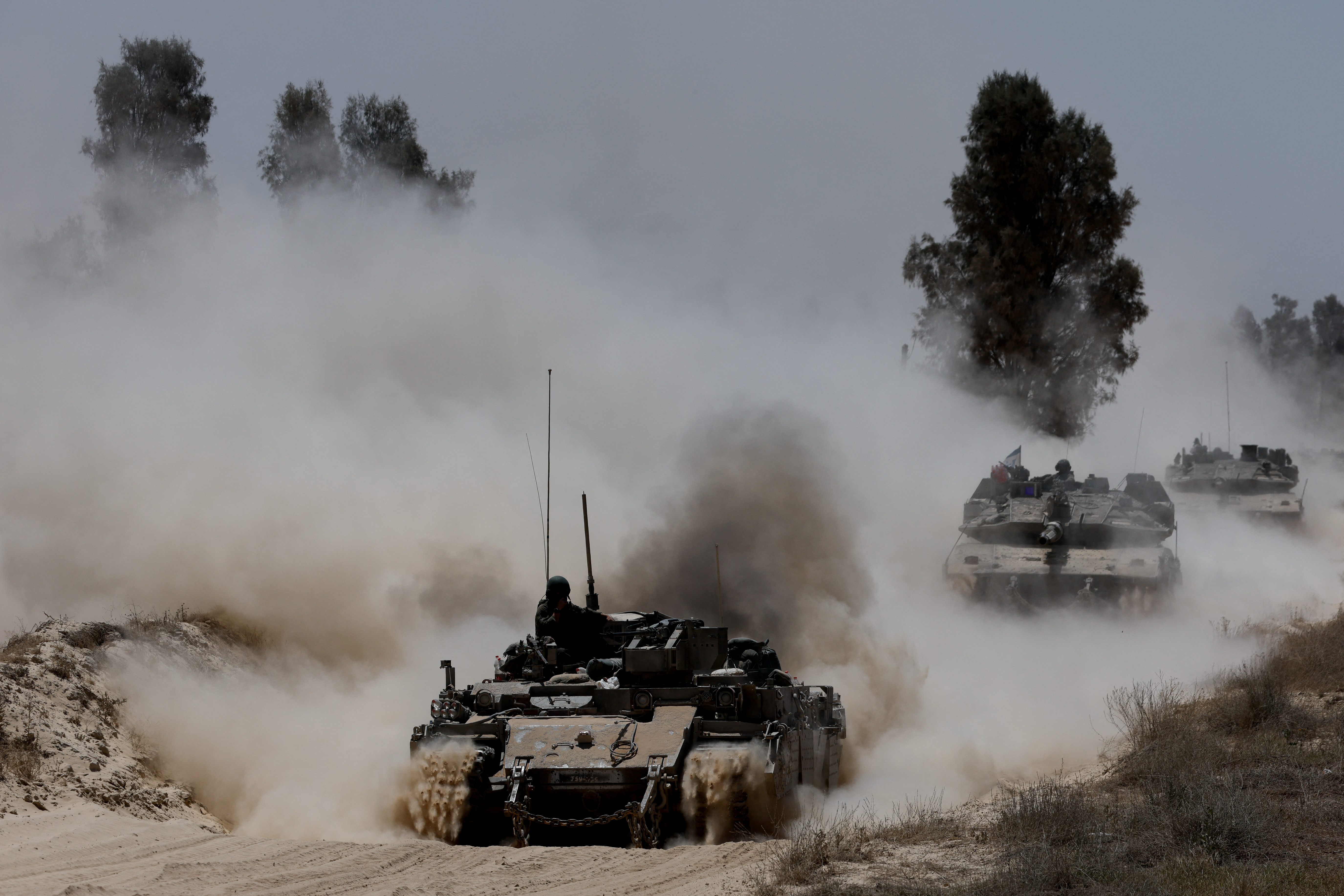 Military vehicles drive their way from the Israeli side of the Israel-Gaza border into Gaza