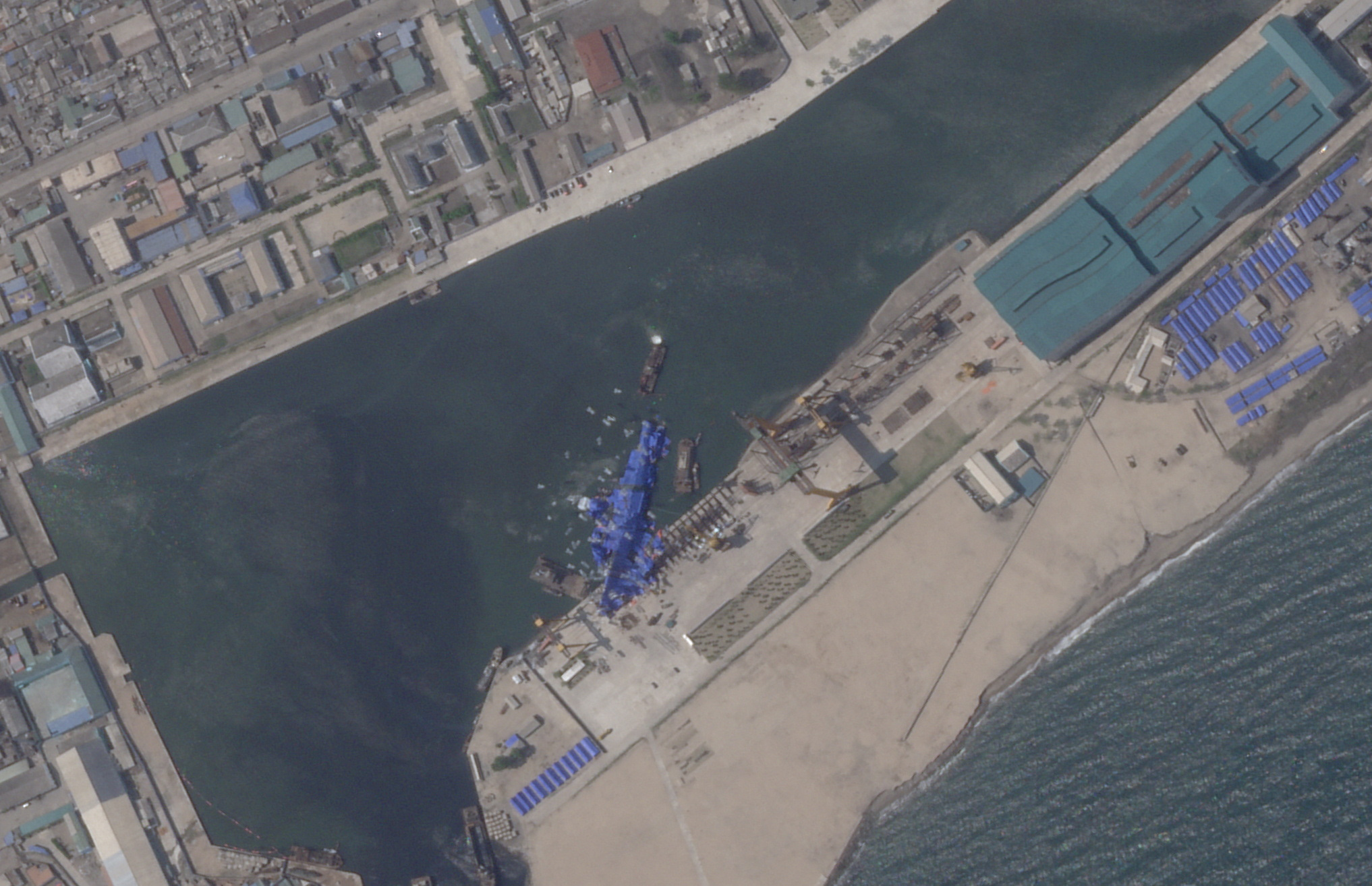 FILE PHOTO: A satellite image shows a North Korean warship covered with a blue tarp after an accident that occurred during its launch at the shipyard in Chongjin