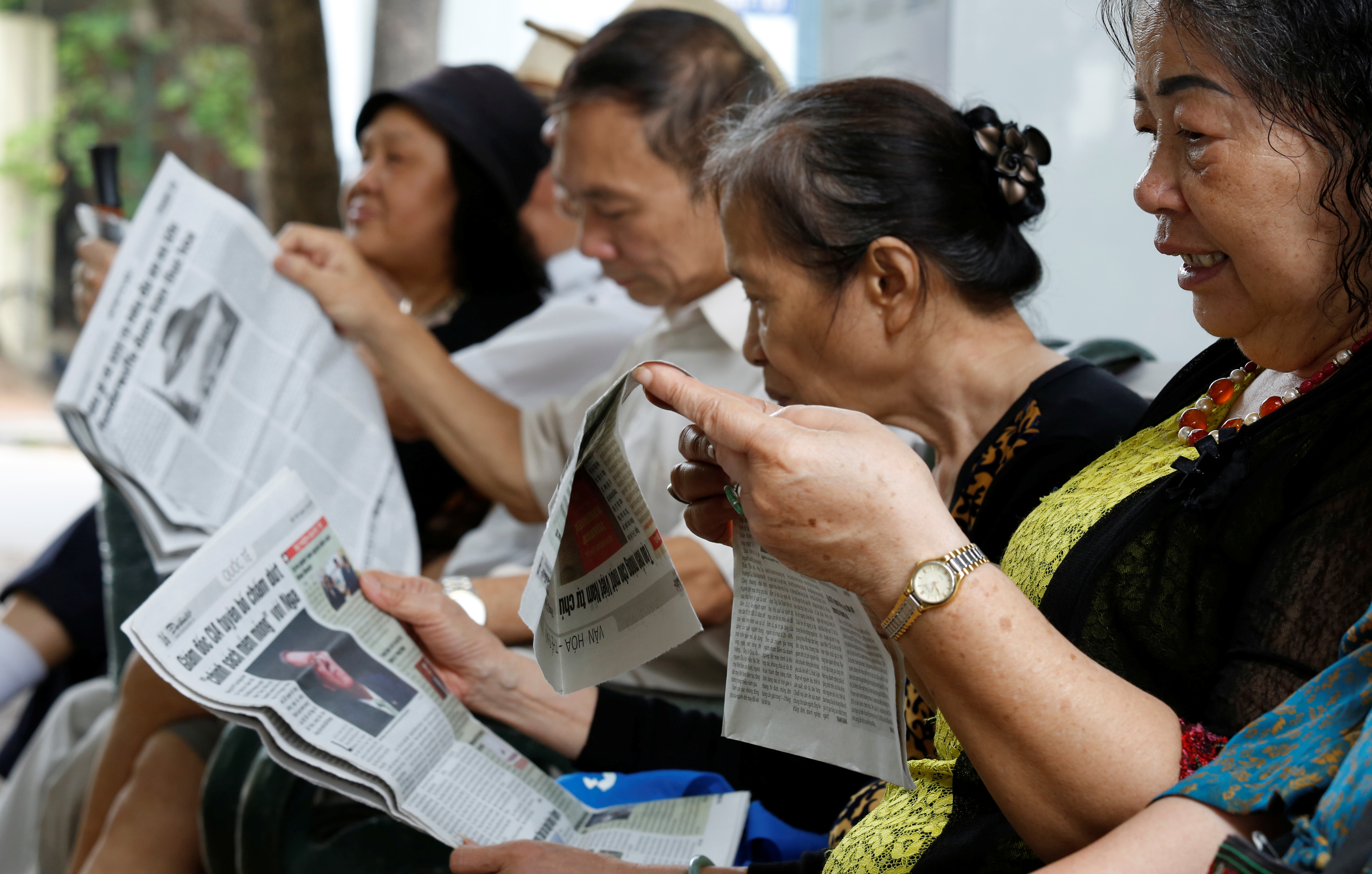 People read newspapers by the Hoan Kiem lake in Hanoi, Vietnam