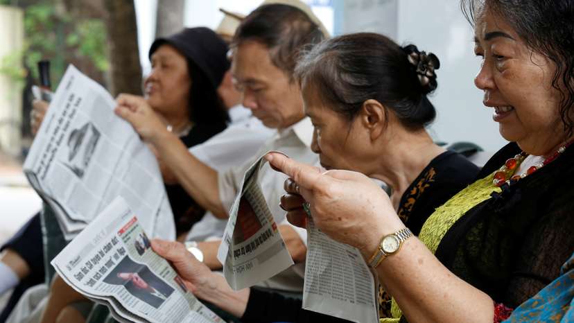 People read newspapers by the Hoan Kiem lake in Hanoi, Vietnam