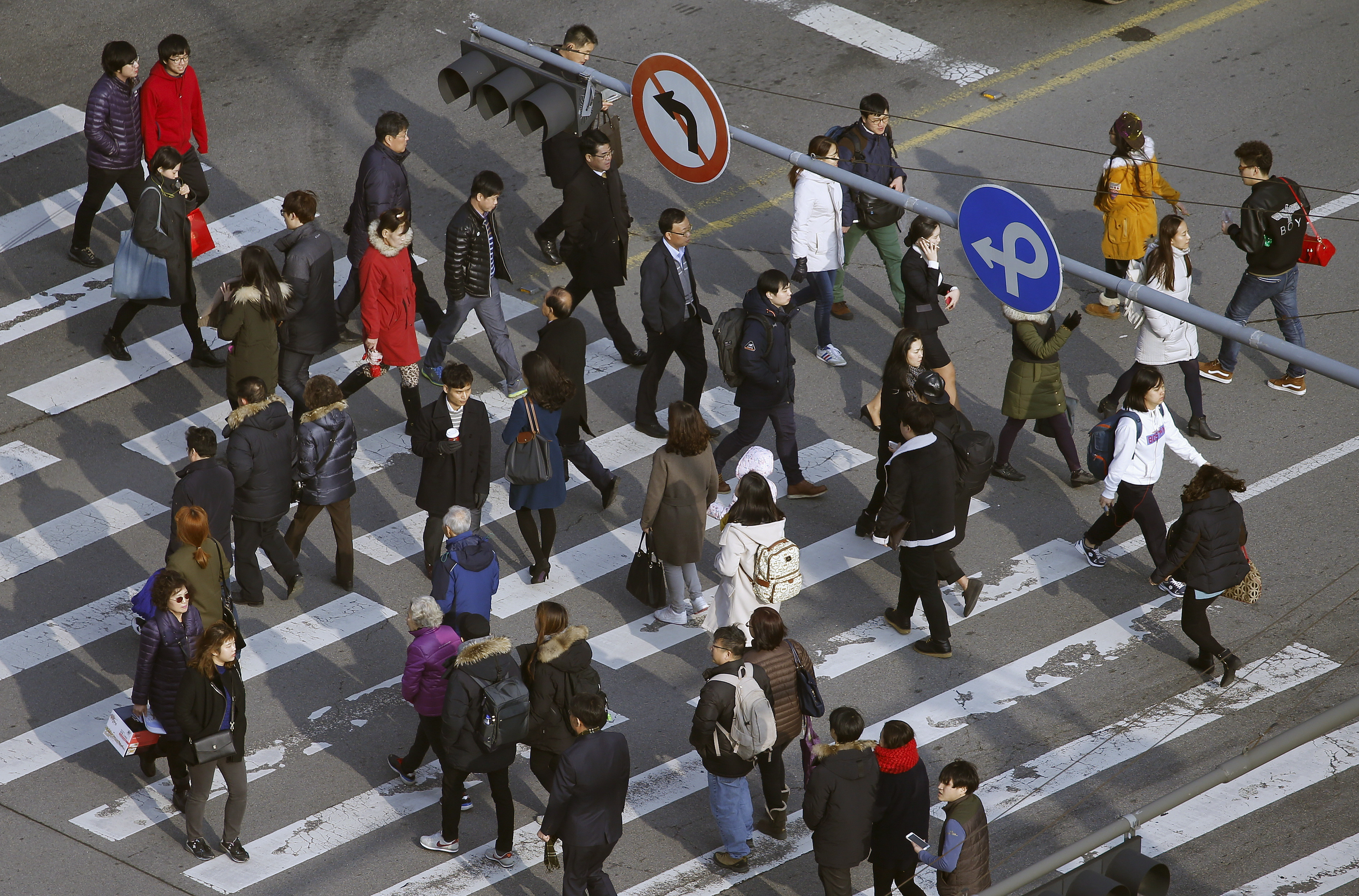 People cross a zebra crossing in a business district in central Seoul