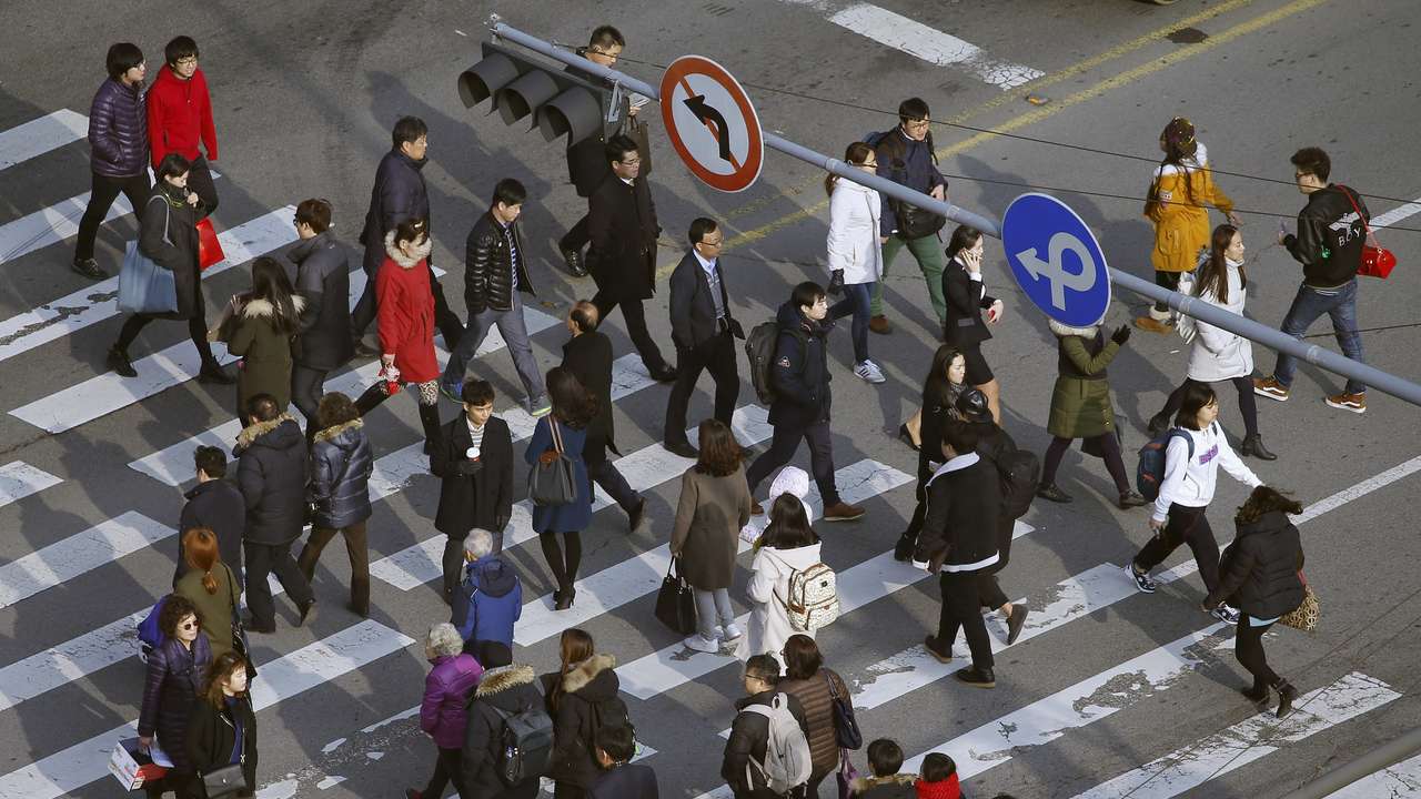 People cross a zebra crossing in a business district in central Seoul