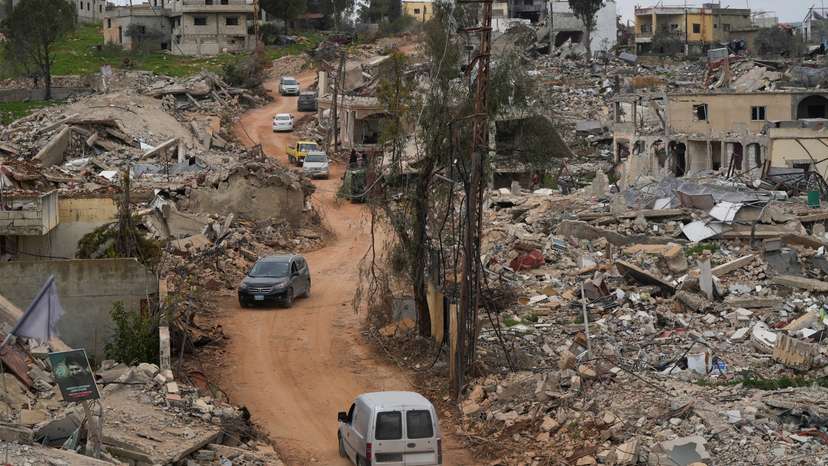 Cars drive past damaged buildings, after Israeli troops withdrew from most of south Lebanon, in Mays al-Jabal