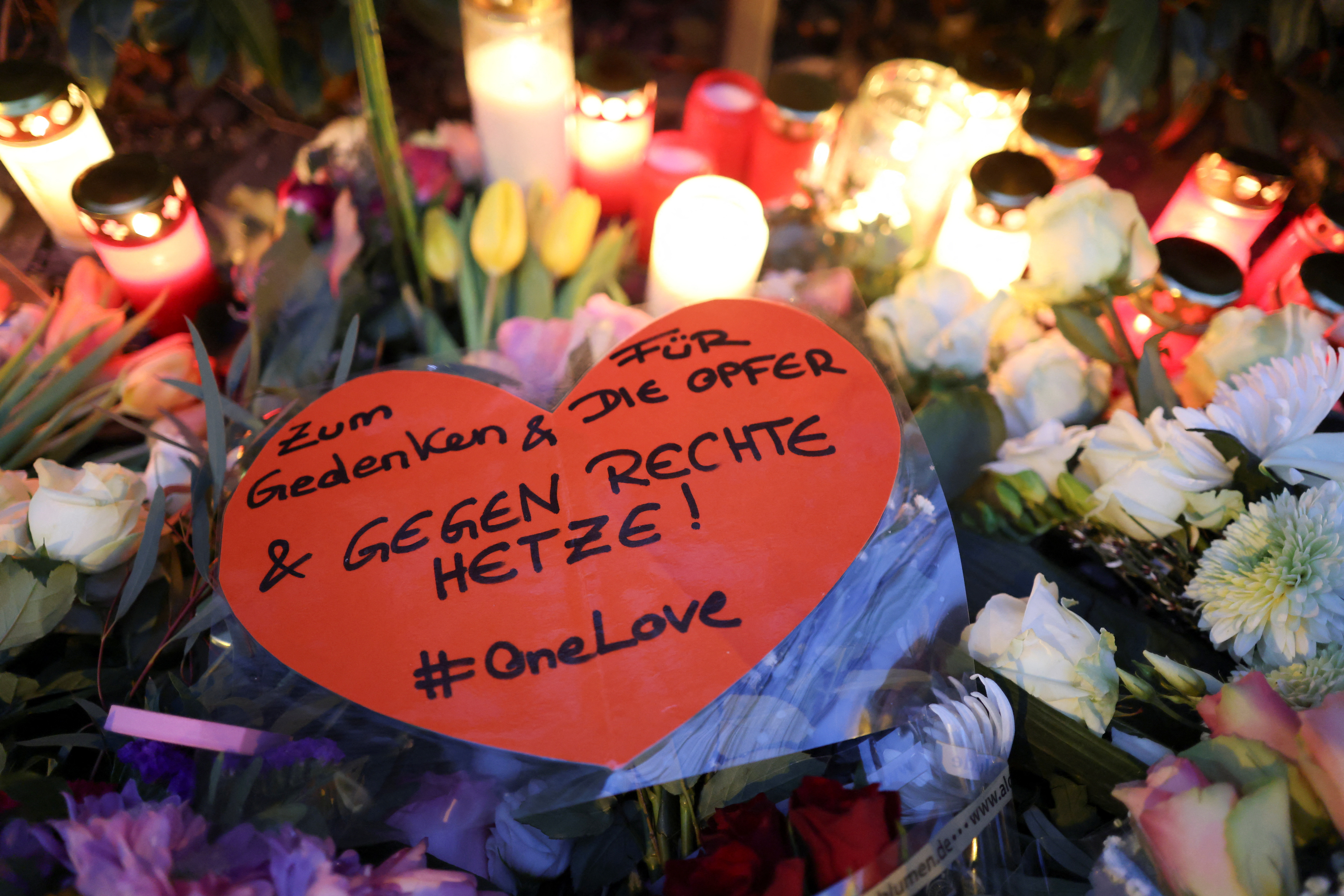 A person places a candle at a makeshift memorial for the victims of a ramming attack, in Munich