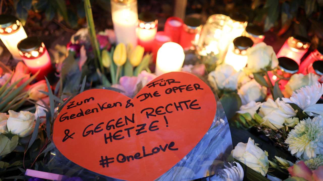 A person places a candle at a makeshift memorial for the victims of a ramming attack, in Munich