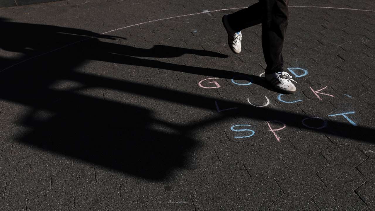 A man walks by a chalked expression on a sidewalk during sunny fall weather at Washington Square Park in New York City