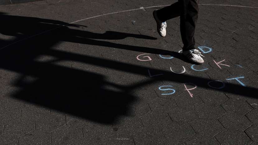 A man walks by a chalked expression on a sidewalk during sunny fall weather at Washington Square Park in New York City