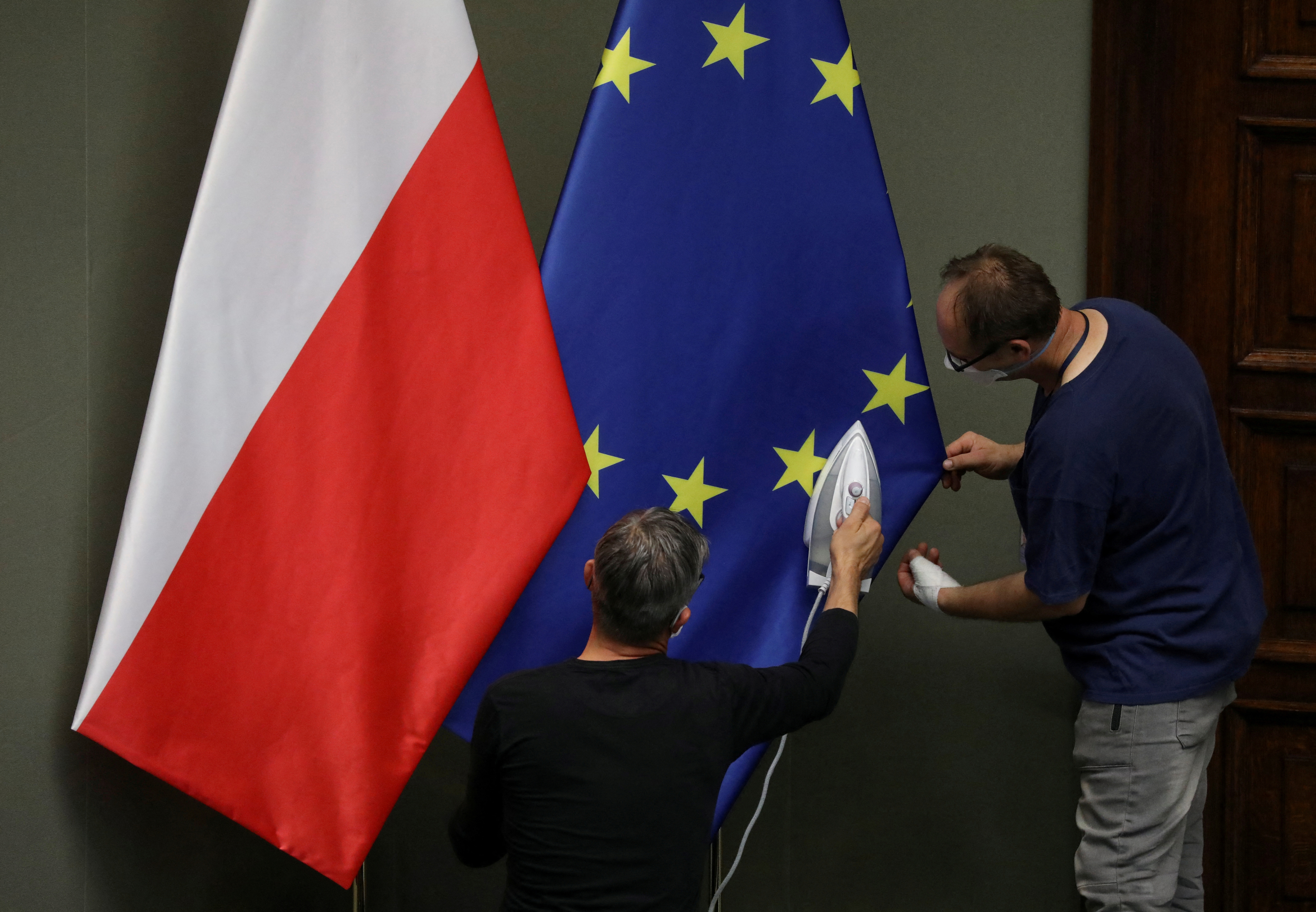 FILE PHOTO: Workers iron flags of European Union and Poland before the swearing-in ceremony of Andrzej Duda as Polish President in Warsaw