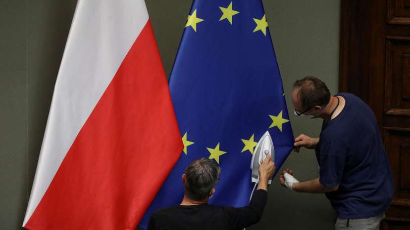 FILE PHOTO: Workers iron flags of European Union and Poland before the swearing-in ceremony of Andrzej Duda as Polish President in Warsaw