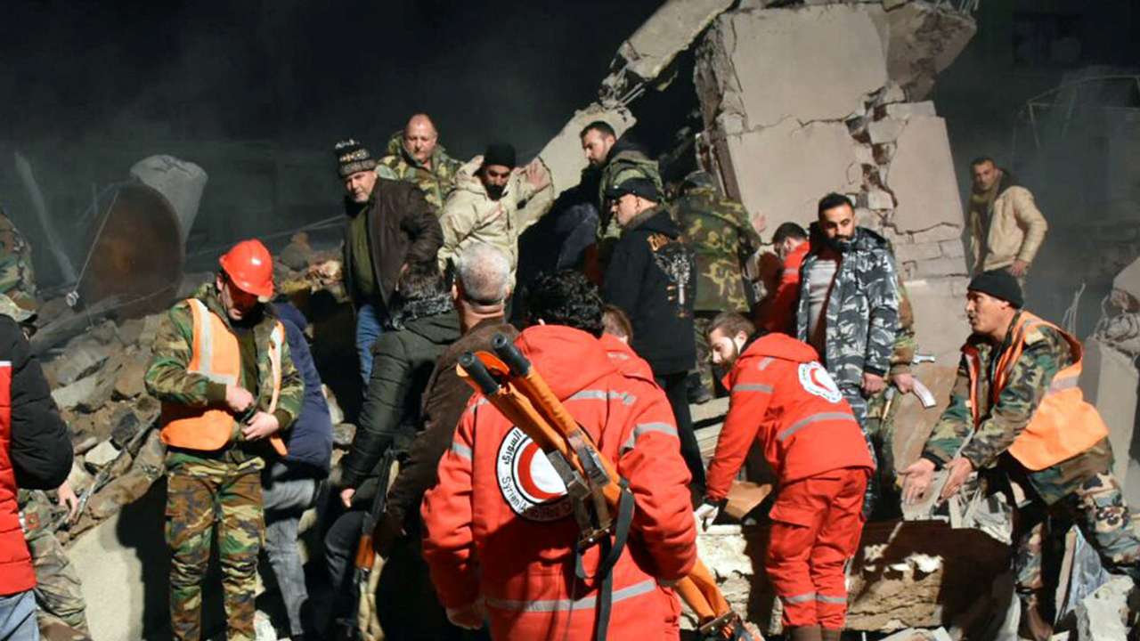 Rescuers search for survivors under the rubble of a damaged building in Homs province