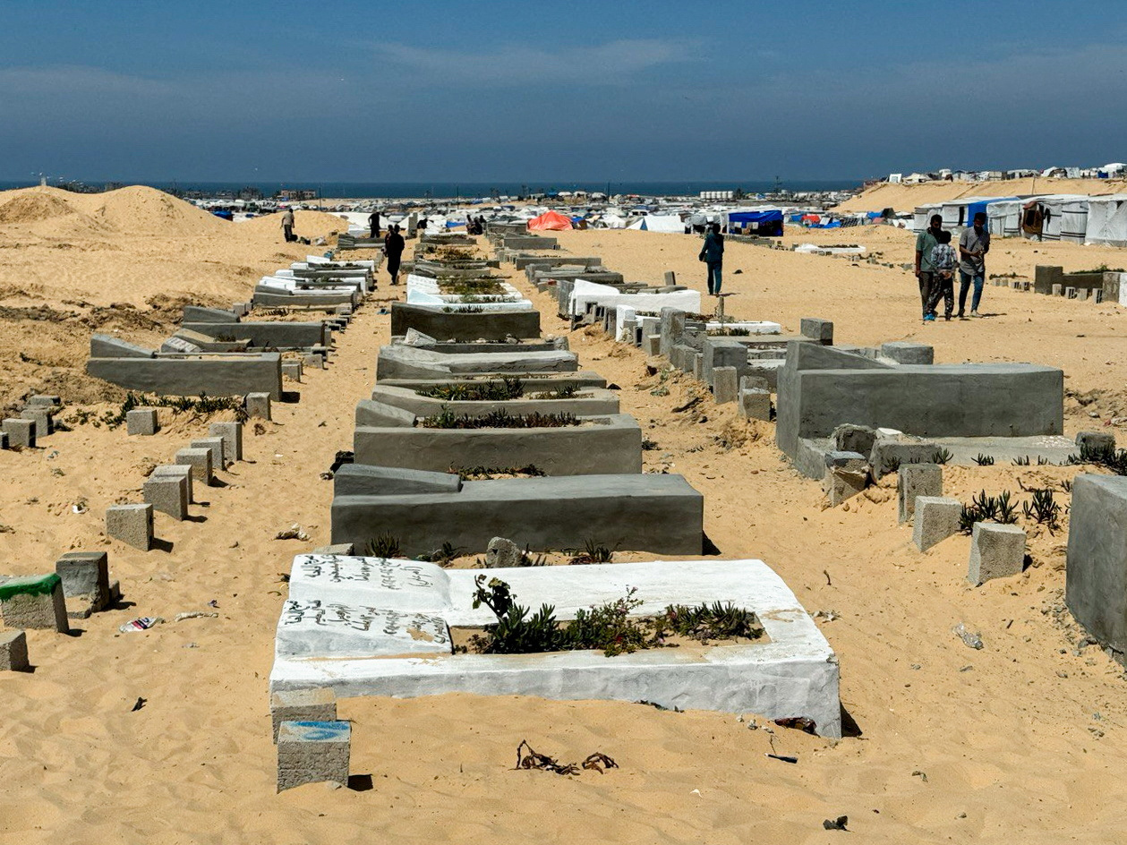 People walk at Muslim graveyard, in Rafah