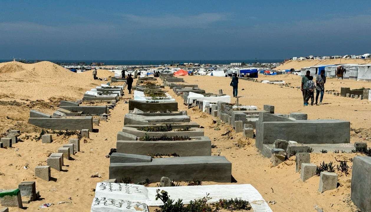 People walk at Muslim graveyard, in Rafah