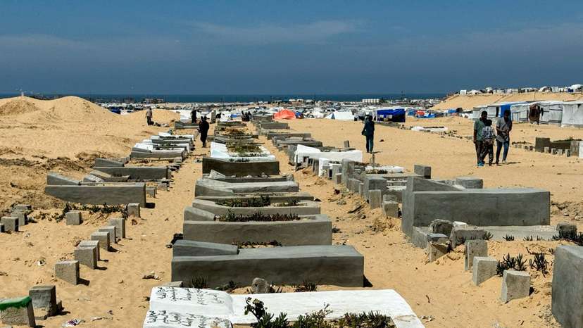 People walk at Muslim graveyard, in Rafah
