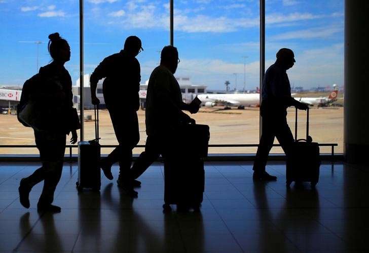 Passengers walk with their luggage towards departure gates at Sydney International Airport