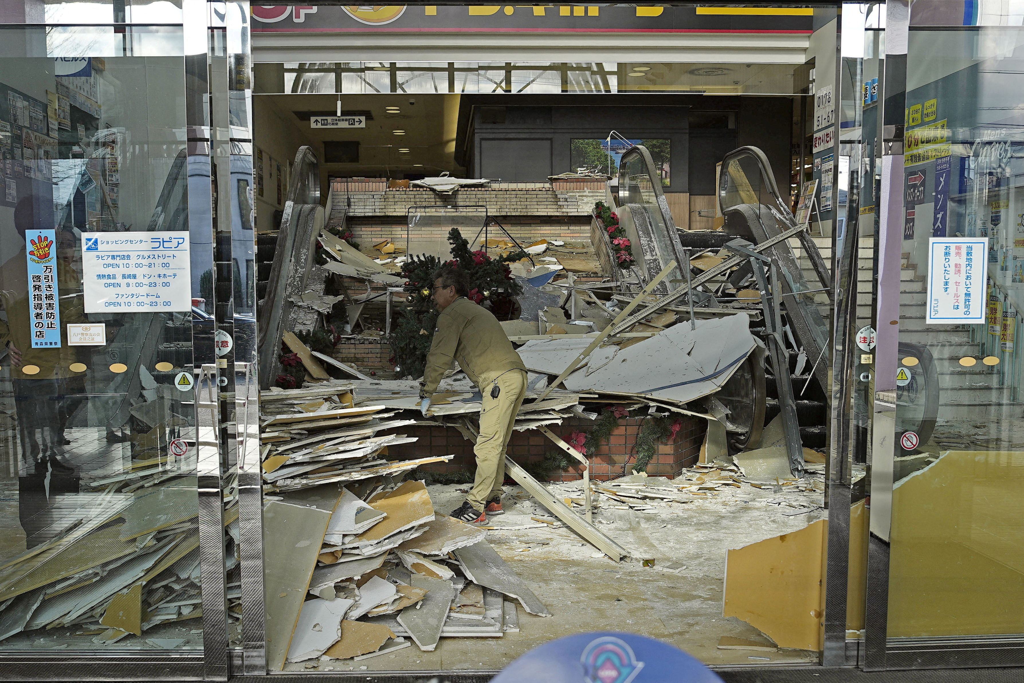 A worker cleans up inside a commercial facility in Hachinohe following a strong earthquake the previous night