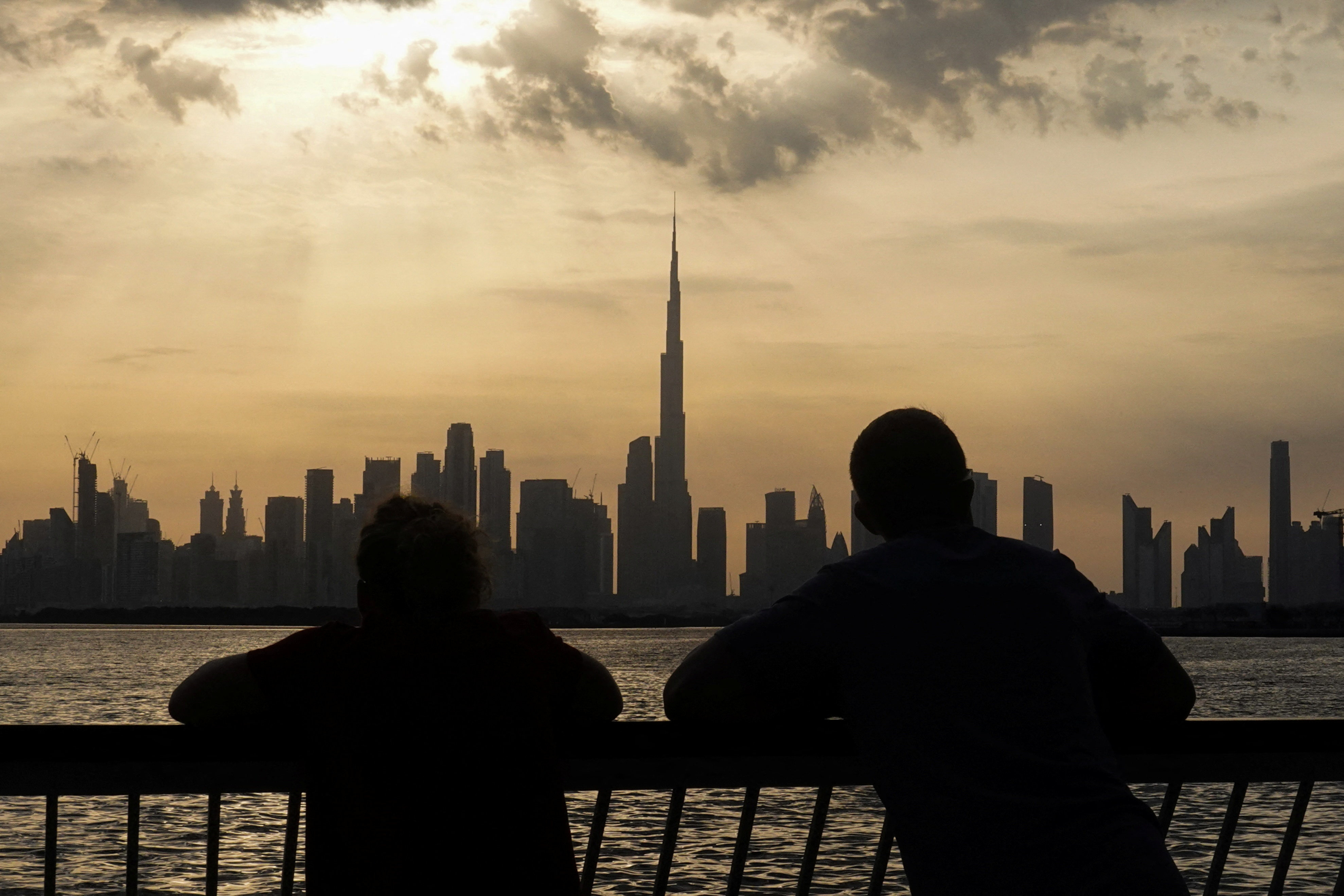 People way the sunset over Dubai, with a general view of the Dubai skyline, including Burj Khalifa, center, amid the U.S.-Israel conflict with Iran