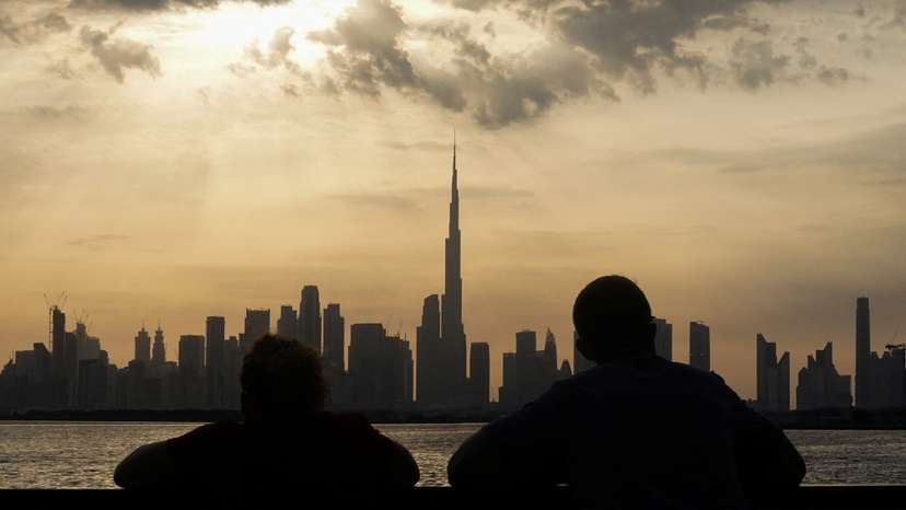 People way the sunset over Dubai, with a general view of the Dubai skyline, including Burj Khalifa, center, amid the U.S.-Israel conflict with Iran