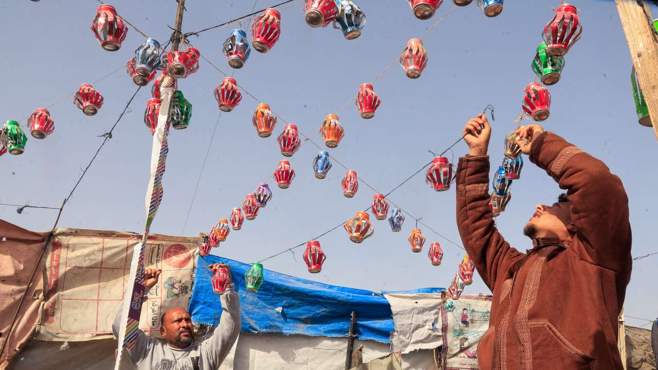 Mohannad al-Najjar hangs Ramadan lanterns made from recycled tin cans on strings between tents, in Khan Younis