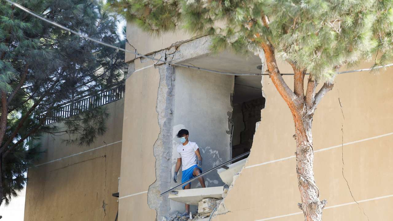 A man stands on a damaged building in the aftermath of an Israeli strike that hit a building, in Wardaniyeh