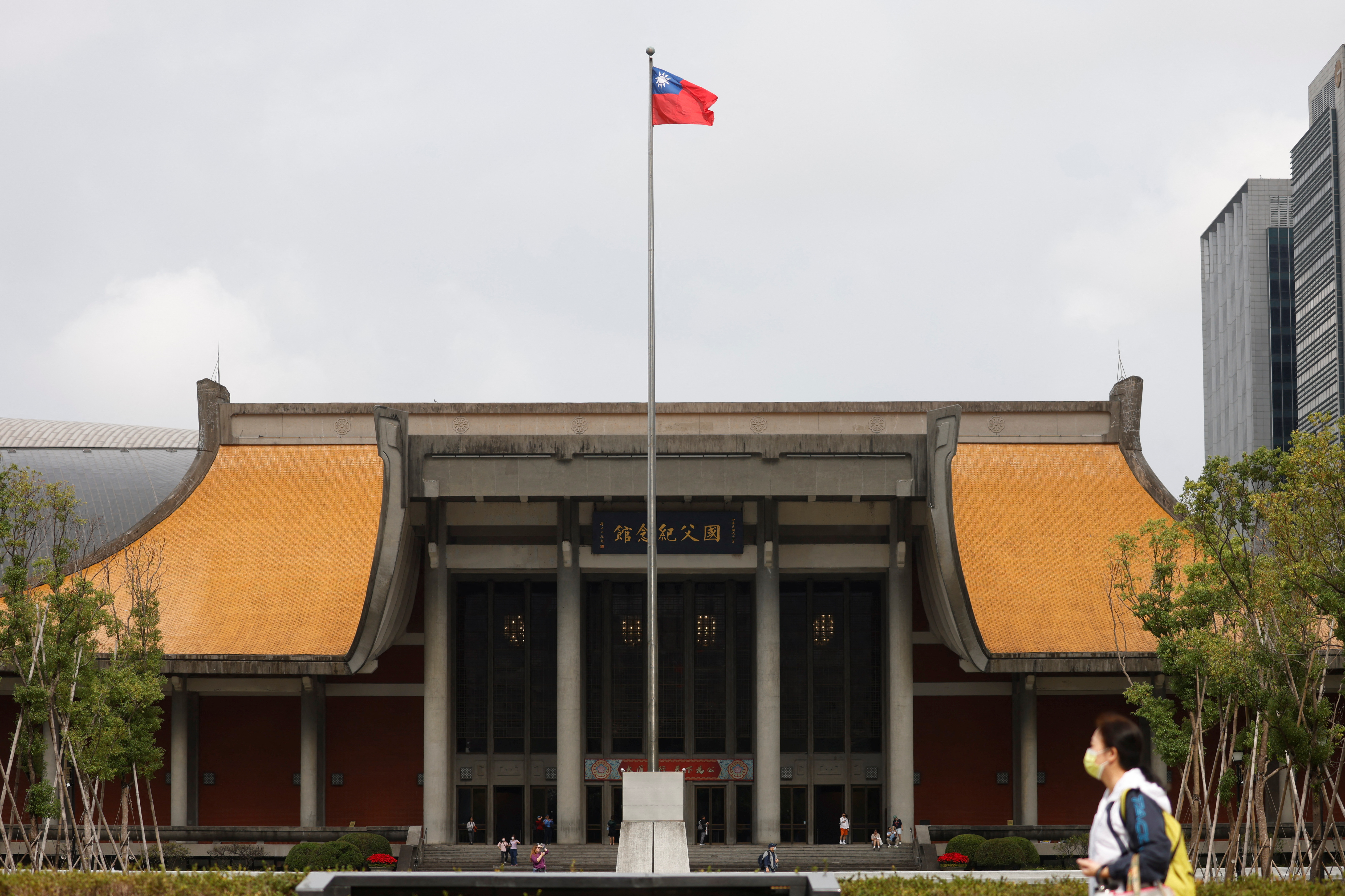 People walk near a fluttering Taiwanese flag outside the Sun Yat-Sen Memorial Hall in Taipei