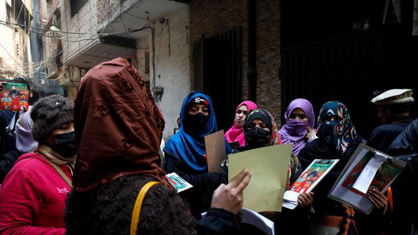 Komal Asghar speaks with fellow teachers before they start a door-to-door campaign, ahead of the general elections in Lahore
