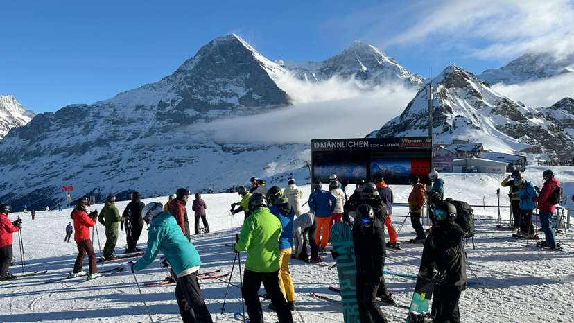 Skiers are pictured near a Mannlichen signboard in front of the Eiger and Monch mountains, in the alpine ski resort of Wengen