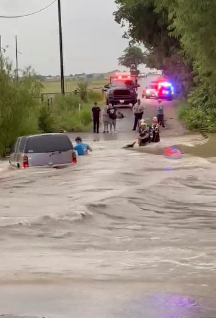 Rescuers help a stranded person following a flood in McGregor