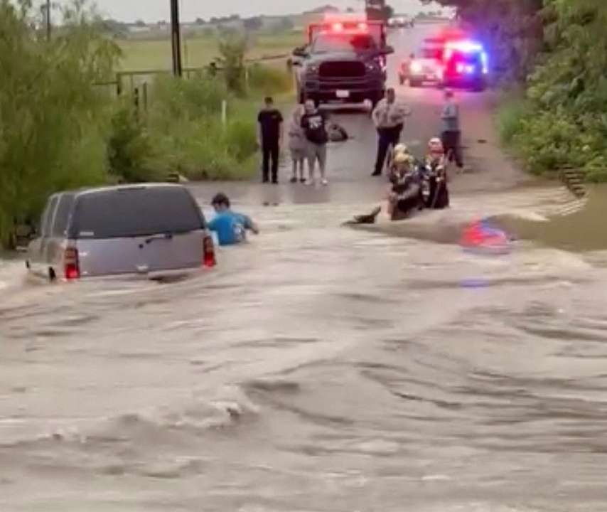 Rescuers help a stranded person following a flood in McGregor