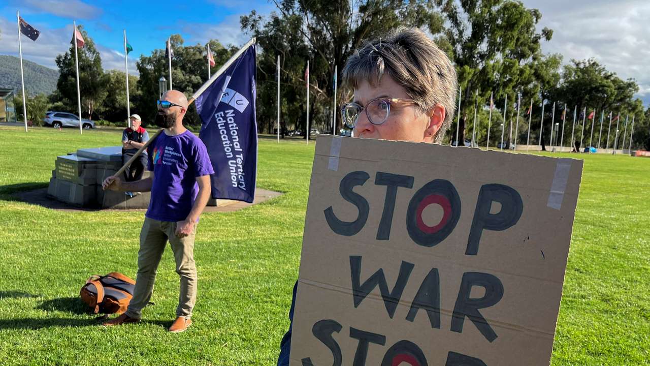 Anti-AUKUS protesters stand outside Australia’s parliament, in Canberra