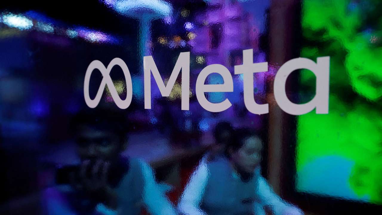 FILE PHOTO: People are seen behind a logo of Meta Platforms, during a conference in Mumbai