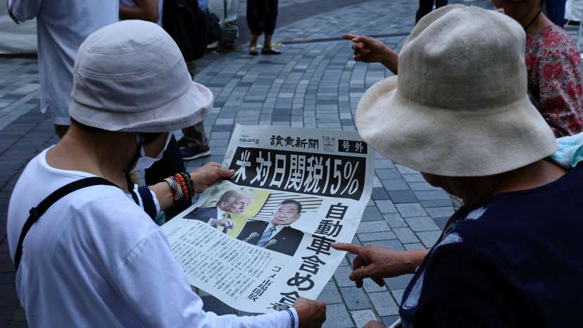 People react as they read a special edition of Yomiuri Shimbun newspaper reporting the tariff deal agreement between U.S and Japan, in Tokyo