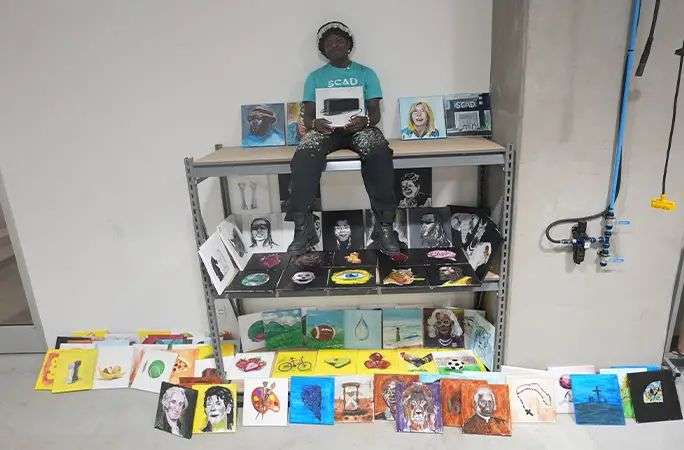 Chancellor sitting among the 106 canvases he painted during his painting marathon